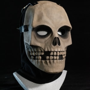 May include: A detailed skull mask with a black fabric covering the back of the head. The mask is made of a light brown material and has a realistic appearance.