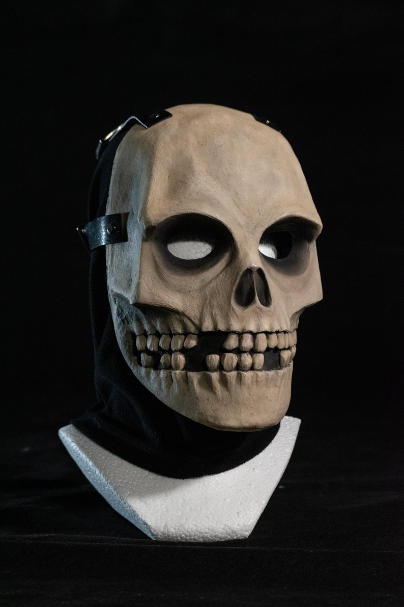May include: A detailed skull mask with a black fabric covering the back of the head. The mask is made of a light brown material and has a realistic appearance.