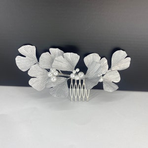 May include: Silver hair comb with a design of ginkgo leaves and pearl accents.