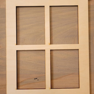 May include: A light-coloured wooden frame with four square apertures. The frame has a simple design and is made of wood. The background is a light brown wooden surface.
