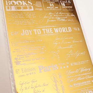 Peut inclure: Une feuille dorée avec divers éléments de texte de style vintage en blanc. La feuille comprend des phrases comme « JOY TO THE WORLD » et « Love & Victory », ainsi que des écritures manuscrites et des dates.
