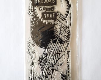 May include: Clear stamp with a feather design and the words "DREAMS come TRUE". The stamp also includes the words "Love peace and harmony" and various decorative patterns. The stamp is in a clear plastic package.