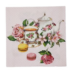 Peut inclure: Une tasse à thé et une théière roses et blanches avec des motifs floraux, entourées de roses roses et de fleurs blanches. Deux macarons, un jaune et un rose, sur un fond rose à pois blancs.