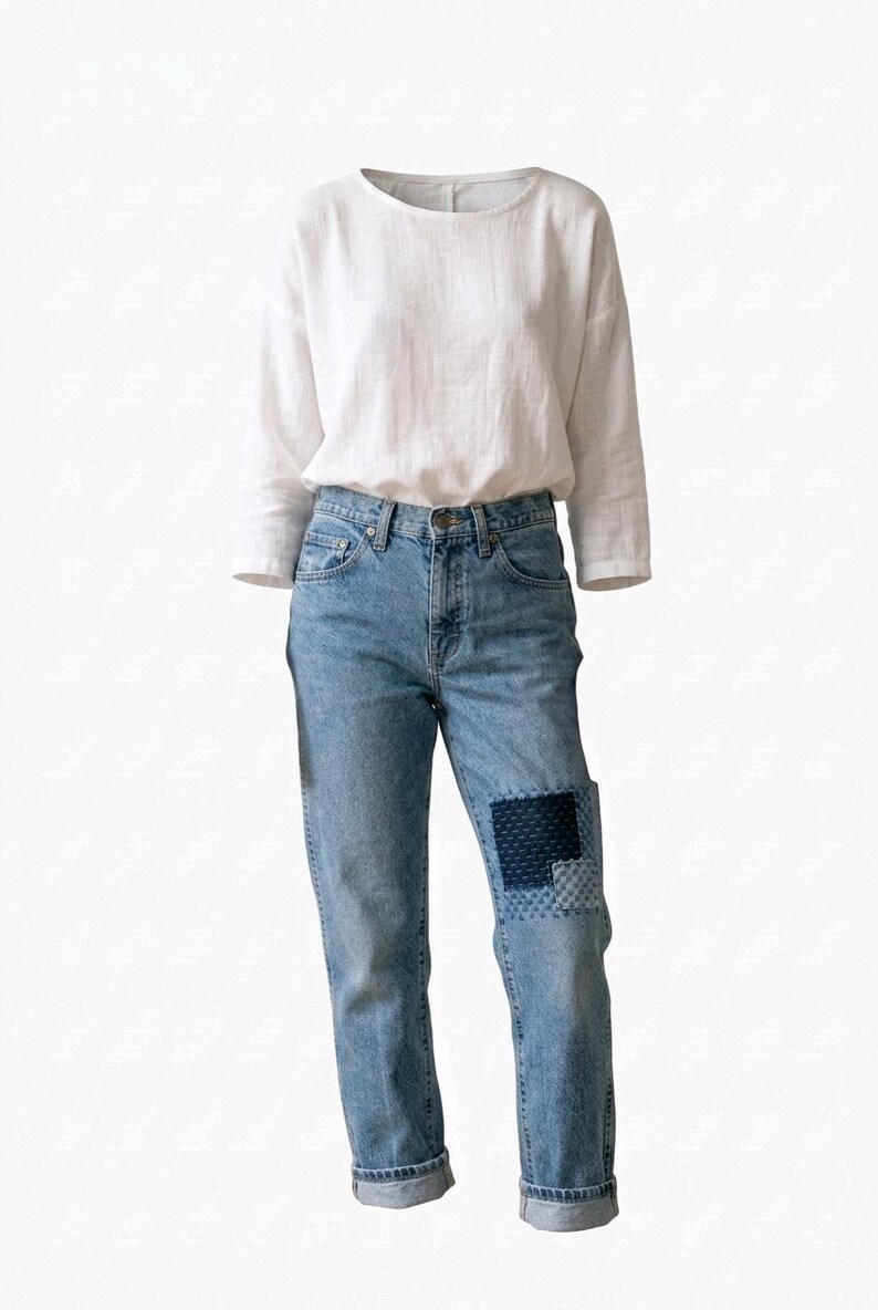 Puede incluir: Un atuendo informal con una camisa blanca de manga larga y vaqueros azul claro. Los vaqueros tienen un detalle de parche en una rodilla y est&aacute;n doblados en los tobillos. La camisa tiene un cuello redondo.