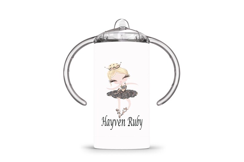 Op de afbeelding: Witte tuitbeker met een ballerina-illustratie. Het ontwerp toont een blonde ballerina in een zwarte tutu en een gouden kroon. De naam "Hayven Ruby" staat eronder gedrukt. De beker heeft doorzichtige handvatten en een doorzichtig deksel.