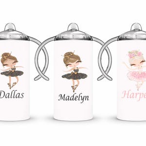 Op de afbeelding: Drie witte tuitbekers met zilveren handvatten en doppen, elk met een ballerina-illustratie. De eerste beker heeft de naam "Dallas", de tweede "Madelyn" en de derde "Harper". De ballerina's dragen tutu's en kronen.