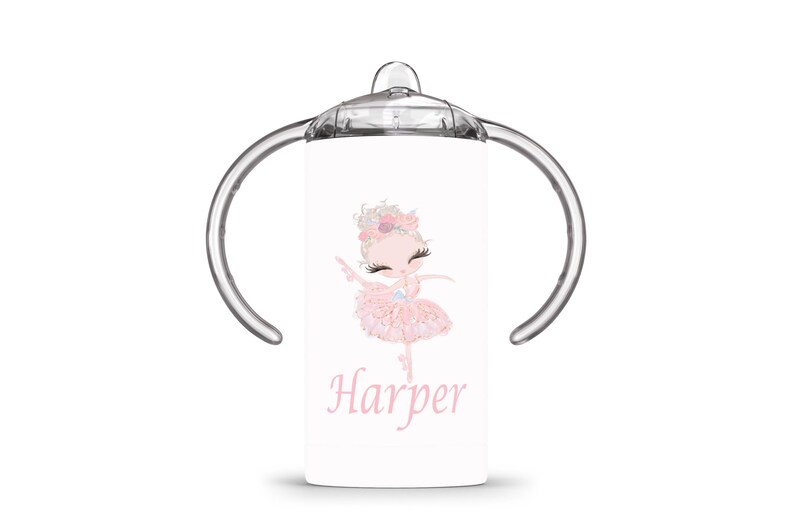 Op de afbeelding: Witte tuitbeker met een roze ballerina-illustratie en de naam "Harper" in roze script. De ballerina draagt een roze tutu en heeft een bloemenhoofddeksel. De beker heeft doorzichtige handvatten en een doorzichtige bovenkant.