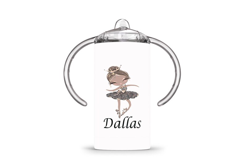 Op de afbeelding: Witte tuitbeker met een cartoon illustratie van een ballerina. De ballerina draagt een kroon en een grijze tutu. De naam "Dallas" is in zwart schrift eronder gedrukt. De beker heeft doorzichtige handvatten en een doorzichtige bovenkant.