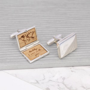 May include: Silver cufflinks with a wooden inlay featuring a world map and the inscription "Daddy, I am with you".