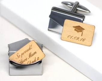 May include: Silver cufflinks with wooden rectangular inserts. One insert features a graduation cap and the date 01.09.16. The other insert has the engraved text "So proud! Love Mum Dad x".