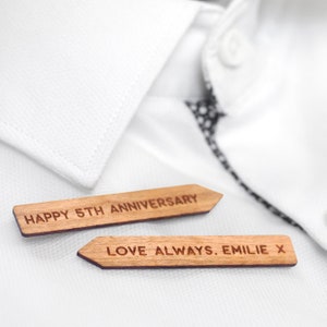 May include: Two wooden signs with pointed ends. The top sign reads "Happy 5th Anniversary". The bottom sign reads "Love Always. Emilie x".