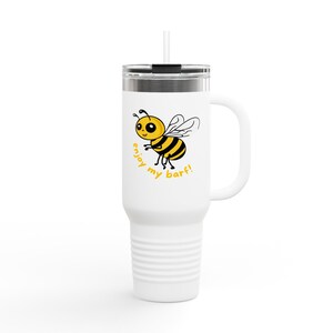 Puede incluir: Un vaso de acero inoxidable blanco con tapa negra y asa. El vaso tiene una abeja de dibujos animados con el texto "enjoy my barf!" impreso en él.