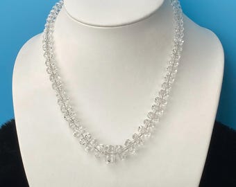 May include: A clear crystal necklace with faceted beads. The necklace is displayed on a white mannequin bust.