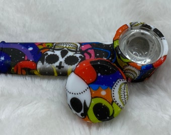 May include: A colourful silicone smoking pipe with a skull design. The pipe has a removable bowl and a mouthpiece.
