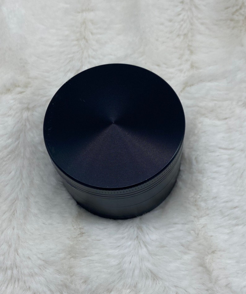 May include: A black metal grinder with a circular top and a textured surface.