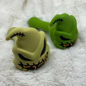 May include: Two silicone pipes shaped like the character Jack Skellington from the movie The Nightmare Before Christmas. One pipe is green and the other is a light green color.