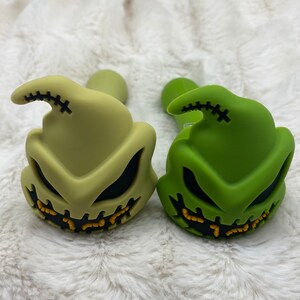 May include: Two silicone smoking pipes shaped like the character Jack Skellington from the movie The Nightmare Before Christmas. One pipe is green and the other is a light green color.