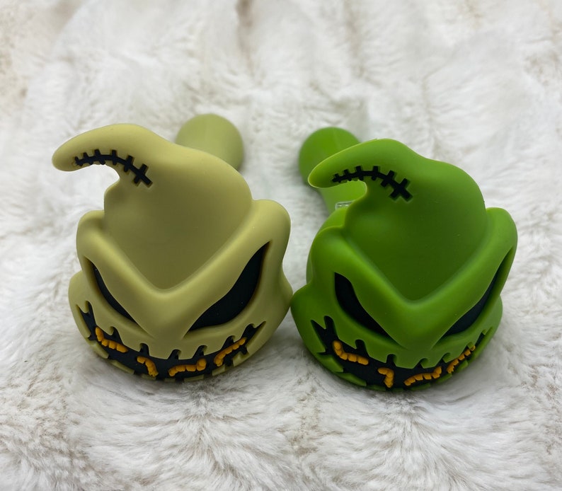 May include: Two silicone smoking pipes shaped like the character Jack Skellington from the movie The Nightmare Before Christmas. One pipe is green and the other is a light green color.