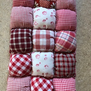 Może przedstawiać: Czerwono-biała poduszka w kratkę z różnymi wzorami, w tym kwiatowymi, kratą i kratą Vichy.