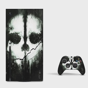 May include: A black and white gaming console and a matching wireless controller featuring a distressed, high-contrast graphic of a skull with dark, ink-like splatters and cracks across the surface, creating a weathered and textured appearance.