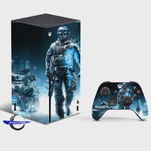 May include: A rectangular gaming console and a wireless controller featuring a blue-toned graphic wrap. The design depicts a soldier in tactical gear walking past a military vehicle against a dark, urban background with the Xbox logo visible.