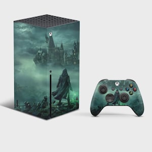 May include: A black gaming console and a matching wireless controller, both featuring a dark, atmospheric graphic print of a hooded figure standing before a large, looming castle under a cloudy, green-tinted sky with shadowy figures below.