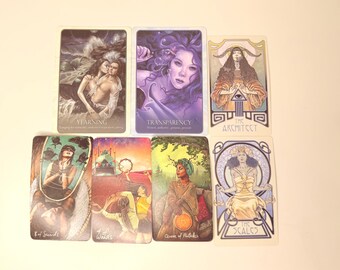 Puede incluir: Un conjunto de cartas de tarot con diversas ilustraciones y texto. Las cartas muestran imágenes de figuras, paisajes y símbolos, con títulos como "Yearning", "Transparency" y "The Architect". La paleta de colores incluye morados, verdes y tonos tierra.
