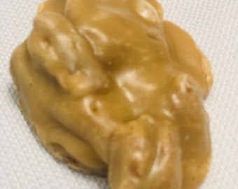 Peut inclure: Un seul bonbon de nougatine aux cacahuètes de forme irrégulière, de couleur brune, avec un glaçage brillant de couleur caramel.
