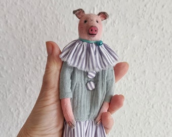 Vintage-style textile pig doll in a blue dress, miniature for the interior on a stand.