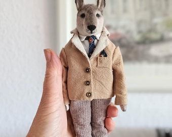 Wolf textile doll in a light-colored jacket and plaid trousers, vintage-style interior toy on a stand