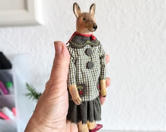 Textile jackal doll on a stand, vintage-style interior toy, girl-jackal in a green dress with pockets.