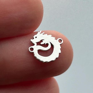 May include: Silver charm featuring a detailed cutout of a dragon curled in a circle.