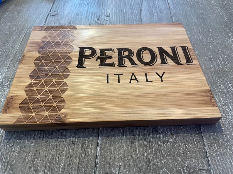 May include: A wooden cutting board with a geometric pattern and the text "PERONI ITALY" engraved on the surface.