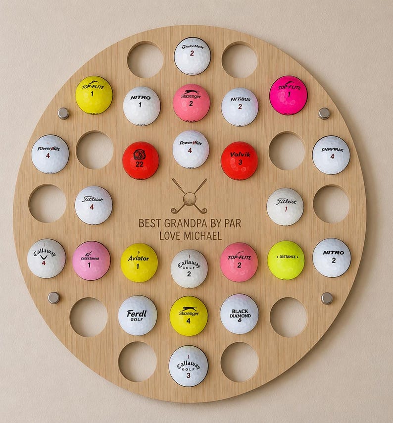 May include: A round wooden golf ball display with 25 golf balls of various brands and colors. The display has a personalized message that reads "BEST GRANDPA BY PAR LOVE MICHAEL".