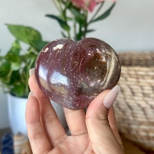 May include: A heart-shaped polished stone with a red, brown, and white marbled pattern.