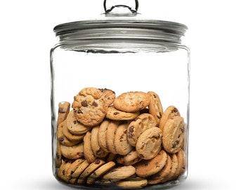 May include: A clear glass cookie jar with a lid filled with chocolate chip cookies.