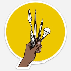 May include: A hand holding a set of four artist's tools, including a paintbrush, a palette knife, a pen, and a brush with a round tip. The tools are held against a yellow background.