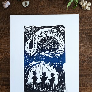 May include: A black and white linocut print of three children standing in a forest with a blue dragon in the sky above them. The print is titled "Imagine Dragons II".