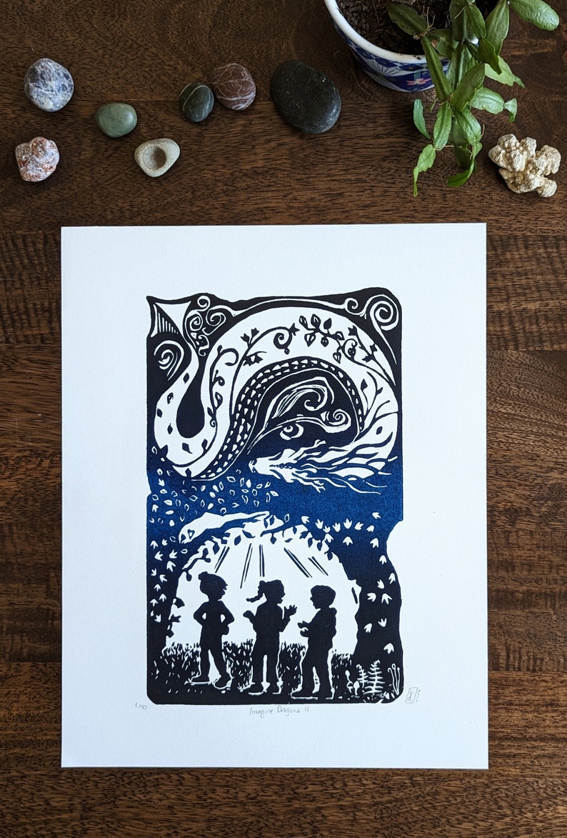 May include: A black and white linocut print of three children standing in a forest with a blue dragon in the sky above them. The print is titled "Imagine Dragons II".