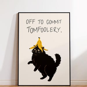 May include: A framed art print showing a black cat with a banana peel hat. The cat is standing upright. The text "OFF TO COMMIT TOMFOOLERY" is written above the cat.