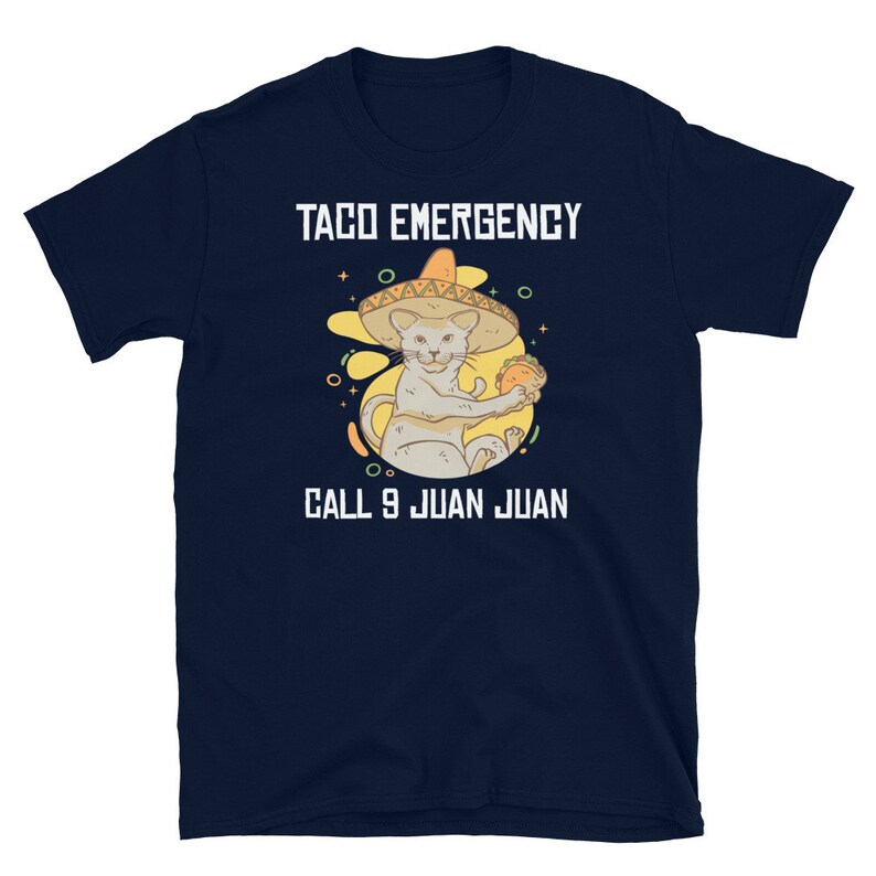 Pode incluir: Uma camiseta azul marinho com um gr&aacute;fico branco de um gato usando um sombrero e segurando um taco. O texto "Taco Emergency Call 9 Juan Juan" est&aacute; impresso na camiseta.