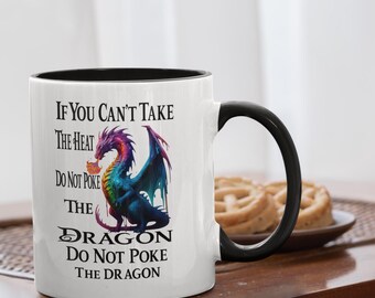 Puede incluir: Taza de cerámica blanca con asa y borde negros, con una colorida ilustración de dragón y el texto "If You Can't Take The Heat Do Not Poke The Dragon." Una divertida taza de café de temática fantástica.