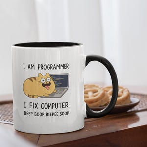 May include: White ceramic mug with a black interior and handle. The mug features a cartoon cat with a laptop and the text "I AM PROGRAMMER I FIX COMPUTER Beep Boop Beepee Boop."