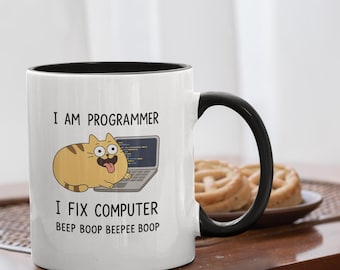 Op de afbeelding: Witte keramische mok met een zwarte binnenkant en handvat. De mok heeft een cartoonkat met een laptop en de tekst "I AM PROGRAMMER I FIX COMPUTER Beep Boop Beepee Boop."