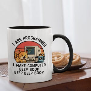 May include: White ceramic mug with a black interior and handle. The mug features a graphic of a cat, computer, and text that reads "I ARE PROGRAMMER I MAKE COMPUTER BEEP BOOP BEEP BEEP BOOP". A fun gift for programmers.