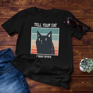 Puede incluir: Camiseta negra con un gráfico vintage de un gato negro y el texto "TELL YOUR CAT I SAID PSSPSPS".