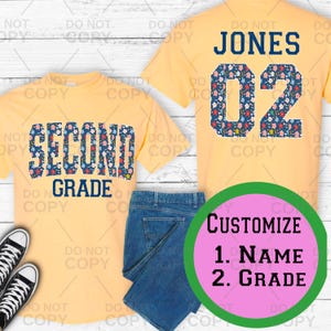 May include: Two pale yellow t-shirts, one with "SECOND GRADE" in a floral design, the other with "JONES" and the number "02" in a floral pattern. Blue jeans and black trainers are also visible. A green and pink circle says "CUSTOMISE 1. NAME 2. GRADE".