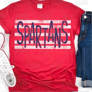 Könnte beinhalten: Ein rotes T-Shirt mit dem Wort "SPARTANS" in Blau auf einem weißen Streifenmuster. Das Shirt wird mit einer blauen Jeans und einem weißen Sneaker gezeigt.