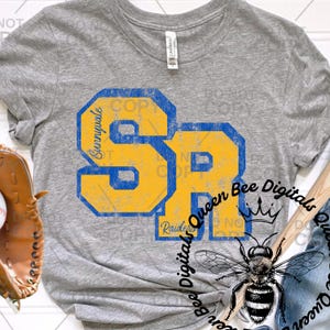 May include: A heather gray t-shirt featuring the letters "SR" in yellow and blue, with "Sunnyvale" and "Raiders" text. The shirt also has a graphic of a bee and the text "Queen Bee Digitals".