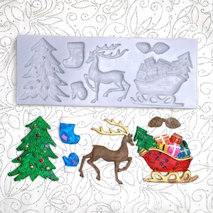 May include: A Christmas-themed silicone mold with various festive shapes, including a Christmas tree, stocking, reindeer, mitten, and a sleigh filled with gifts. The finished products are painted in vibrant colors.